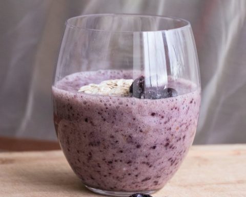 blueberry milkshake in a glass and chia seeds on a table