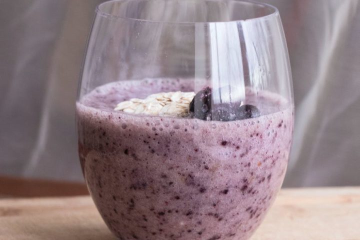 blueberry milkshake in a glass and chia seeds on a table
