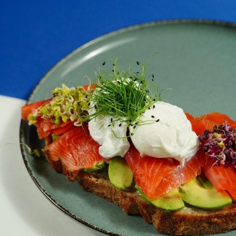 Toast met gerookte zalm en avocado op een bord, een snelle lunch met vette vis en magnesium